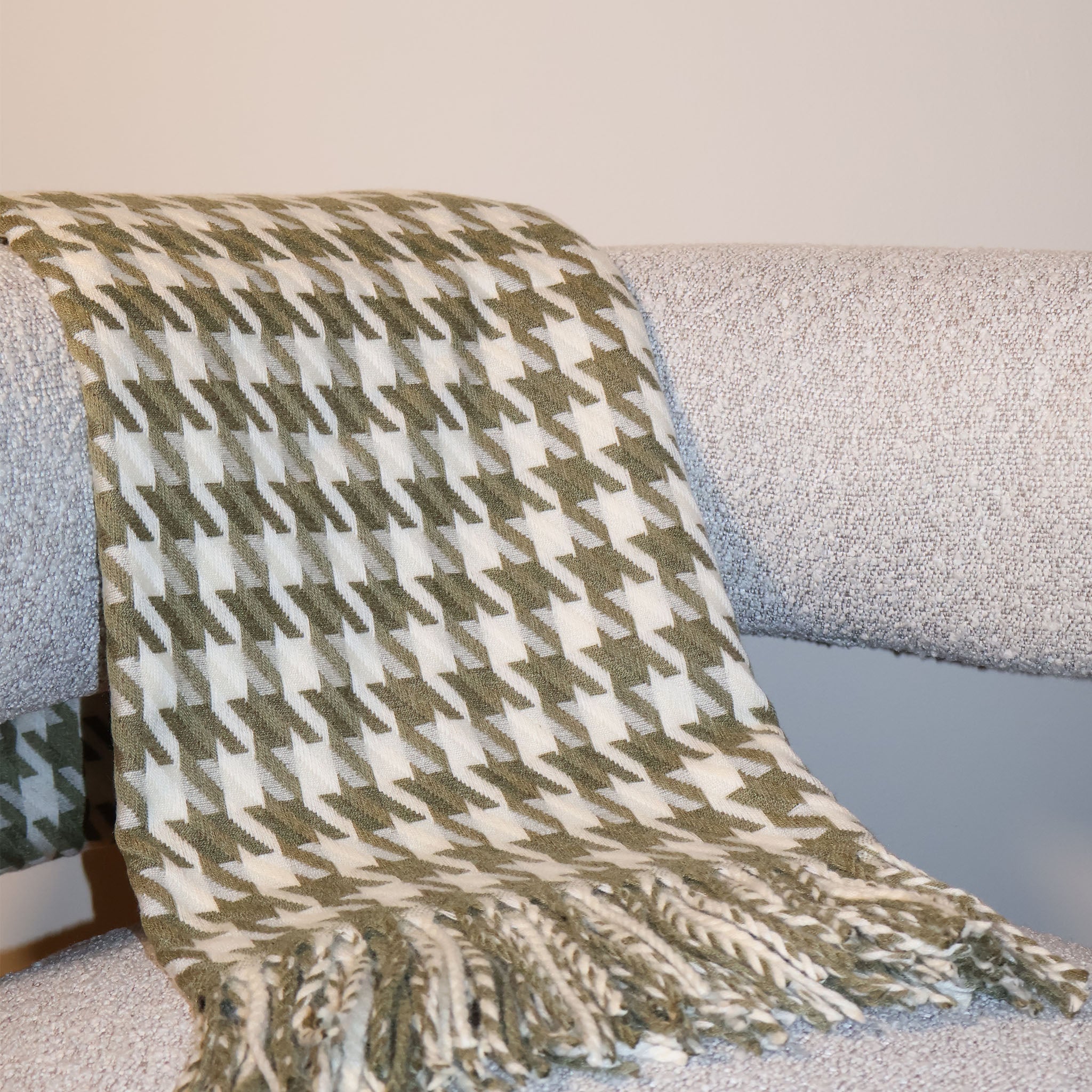 Olive and Cream Houndstooth patterned throw with tassels draped over a chair
