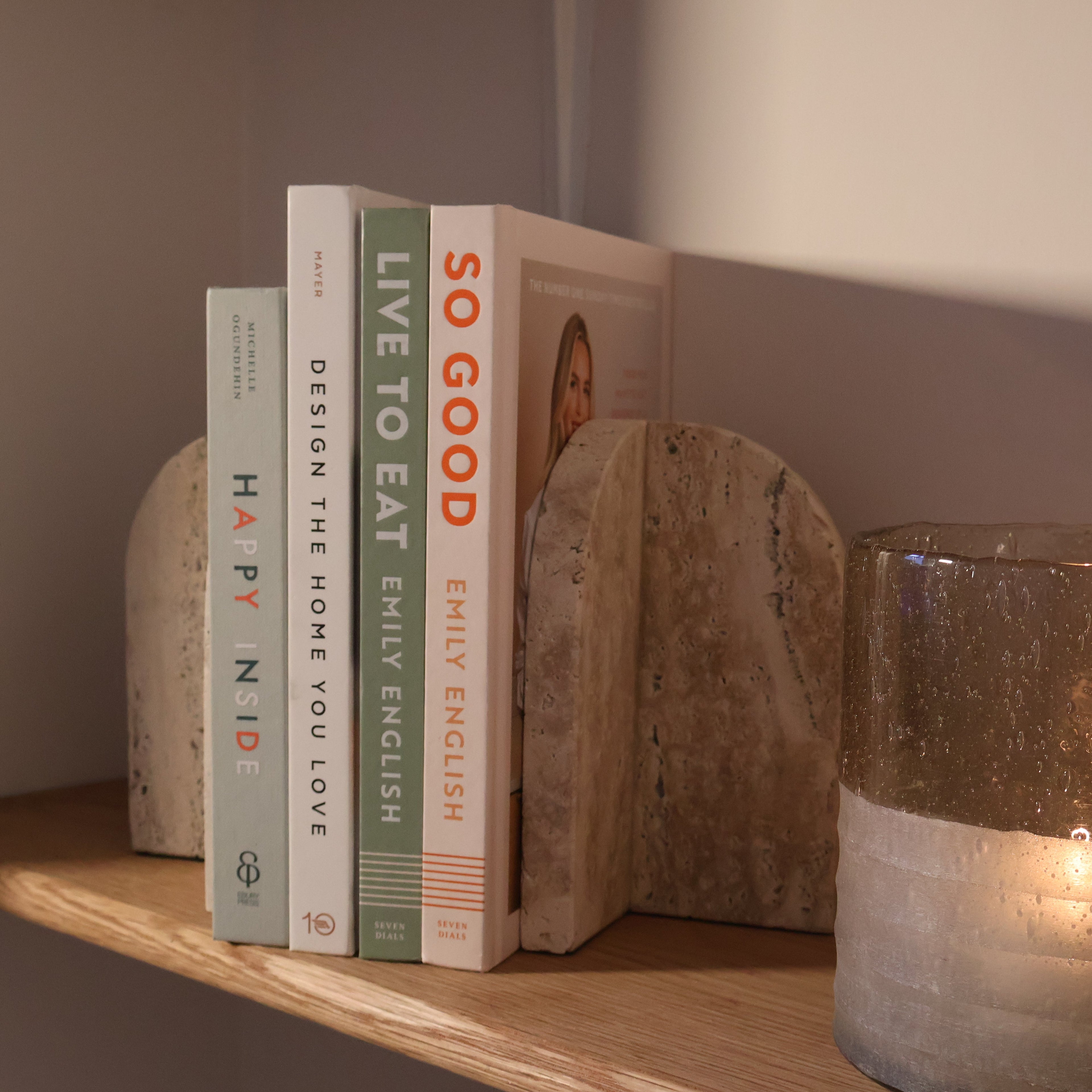 Arched travertine bookends with books and a candle holder 