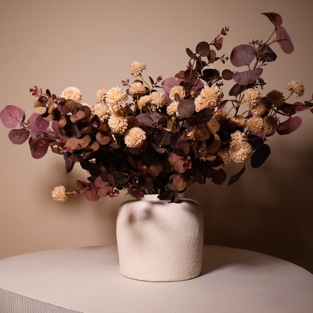 White textured vase with flowers on a coffee table