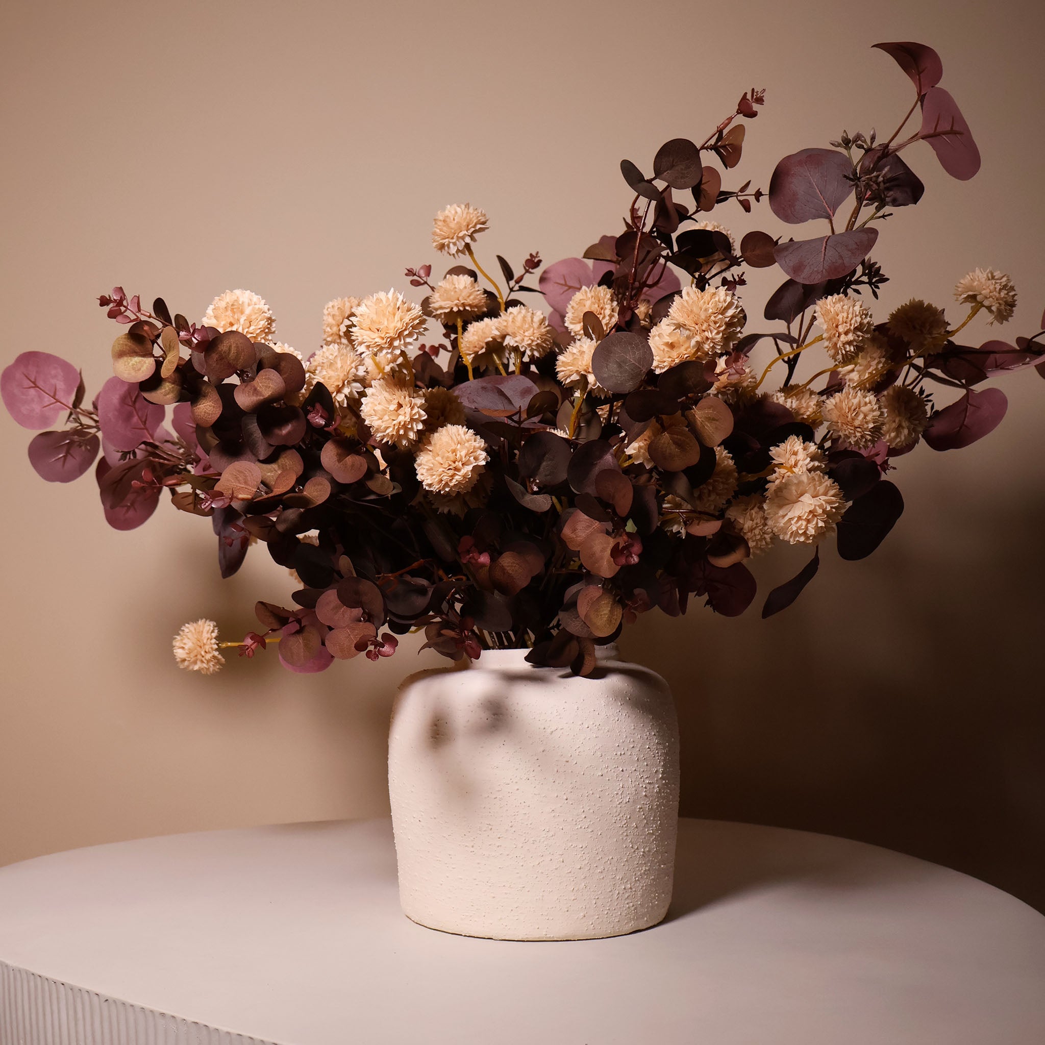 White textured vase with flowers on a coffee table